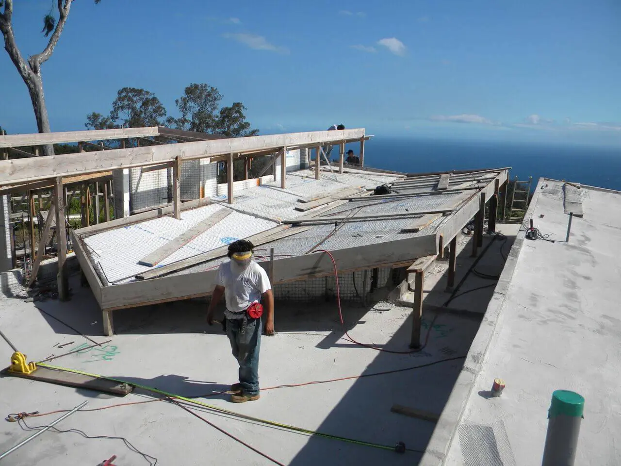 A man standing on the roof of a house with a view of the ocean.