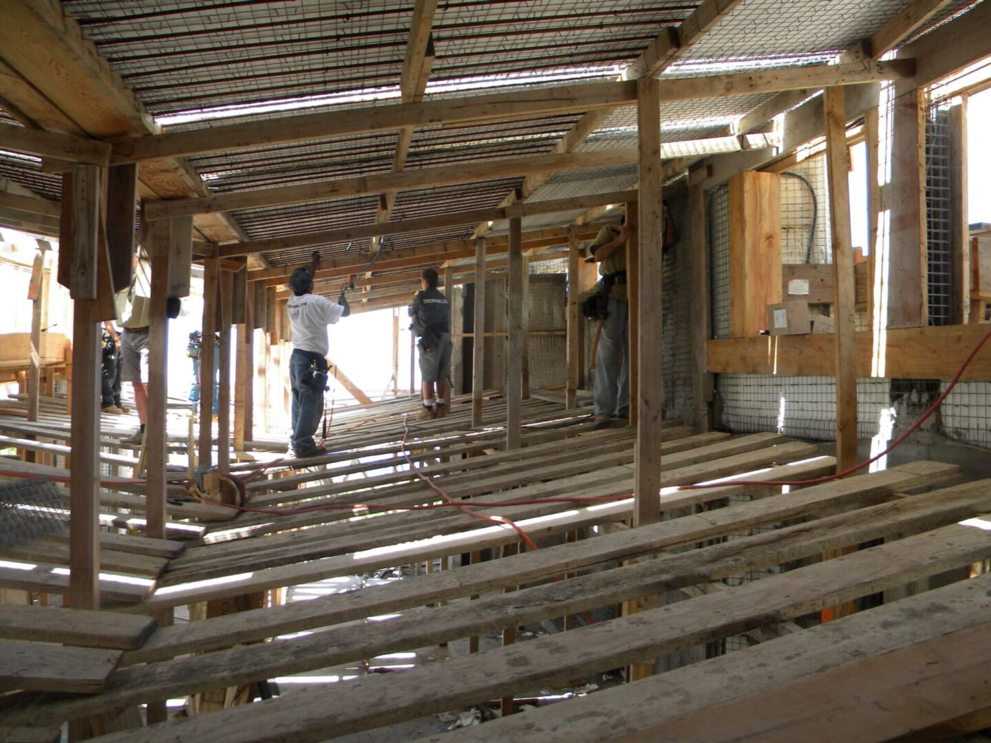 A group of people standing in a room with wooden beams.