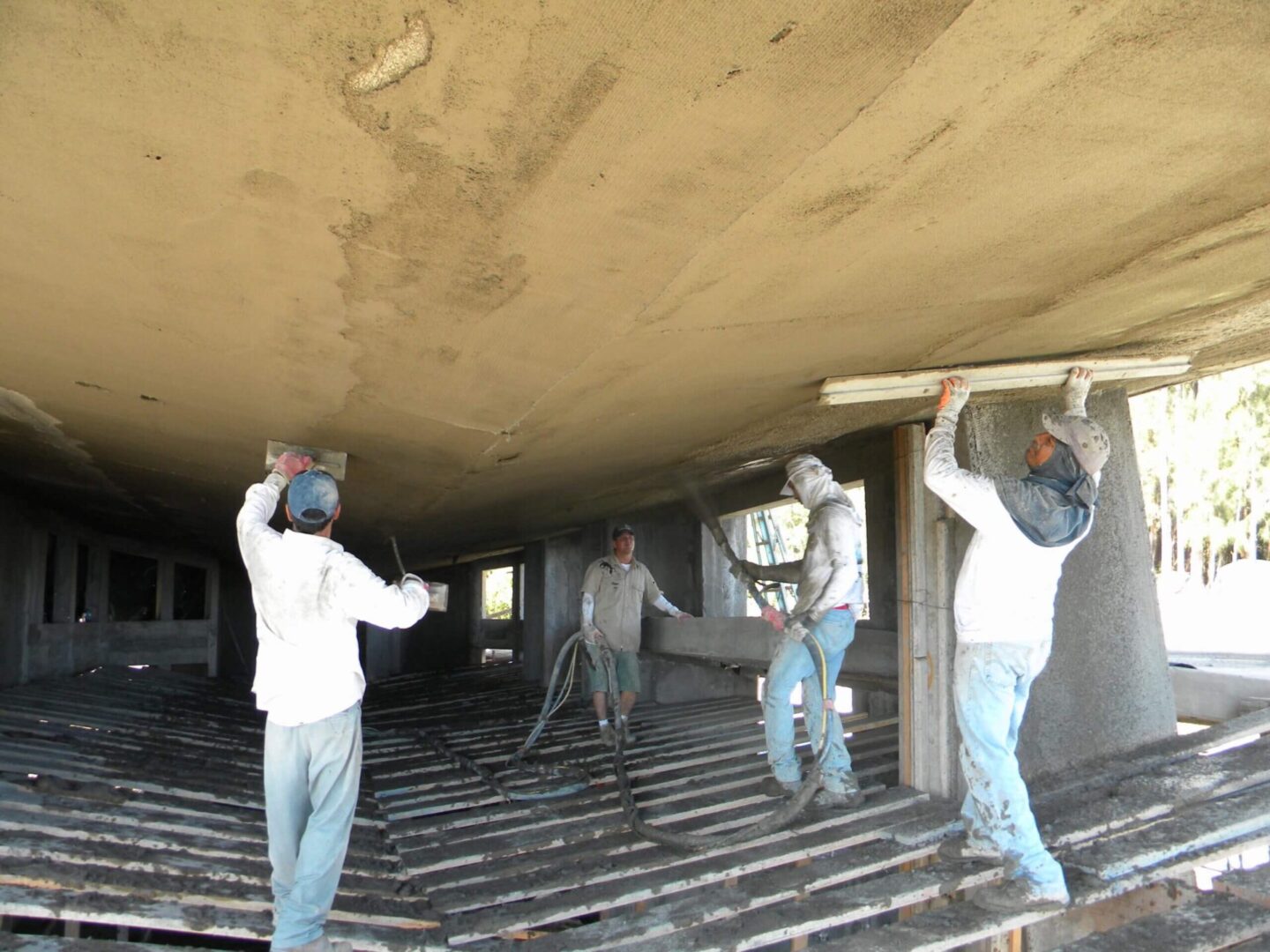 A group of men working on the ceiling of a building.