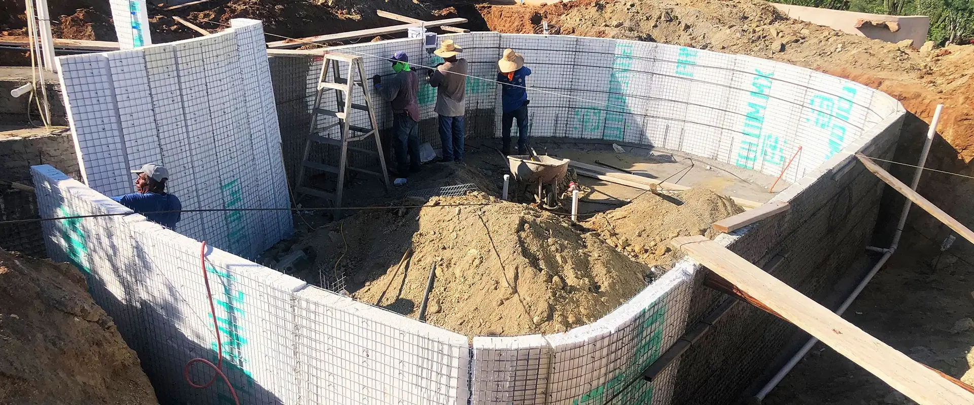 Workers building a pool with concrete blocks.
