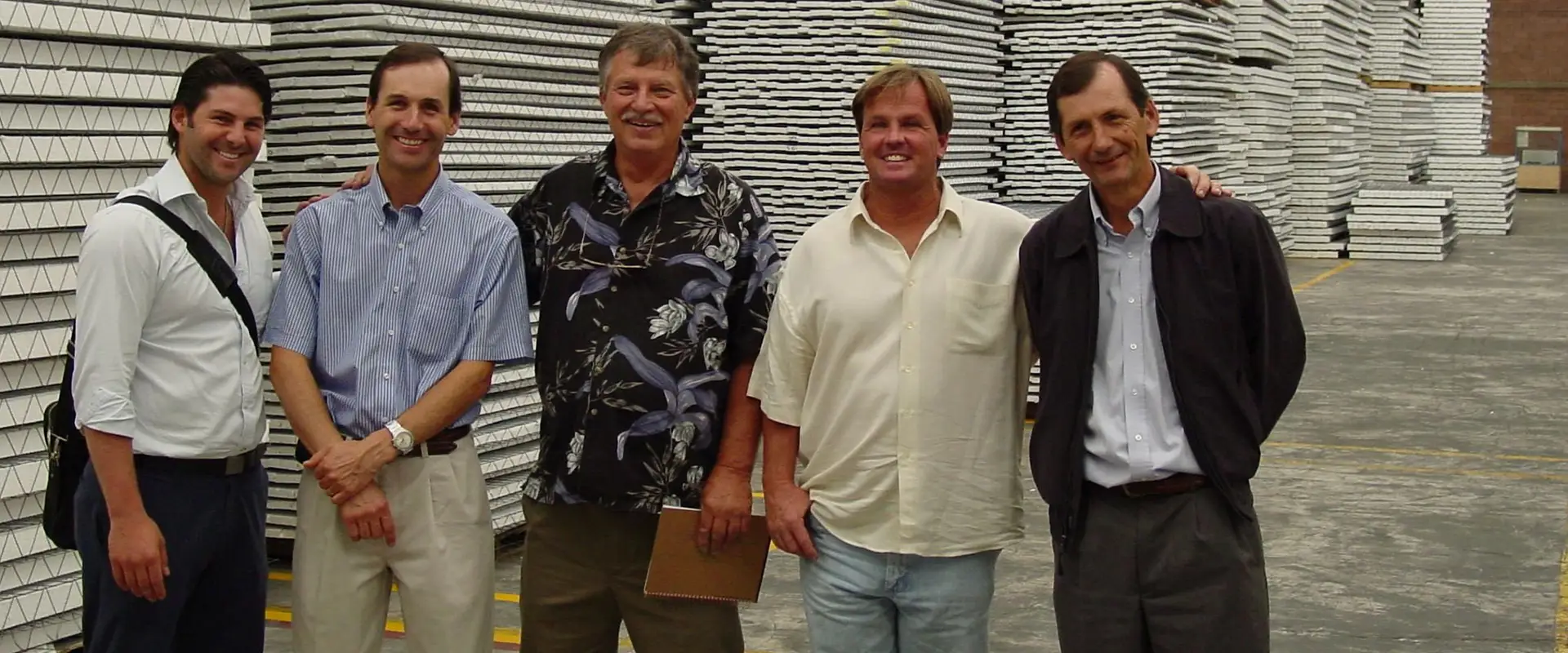Five men smiling in front of stacked boards.