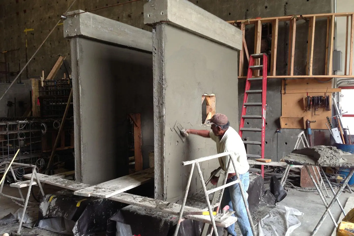 A man is painting the wall of an unfinished building.