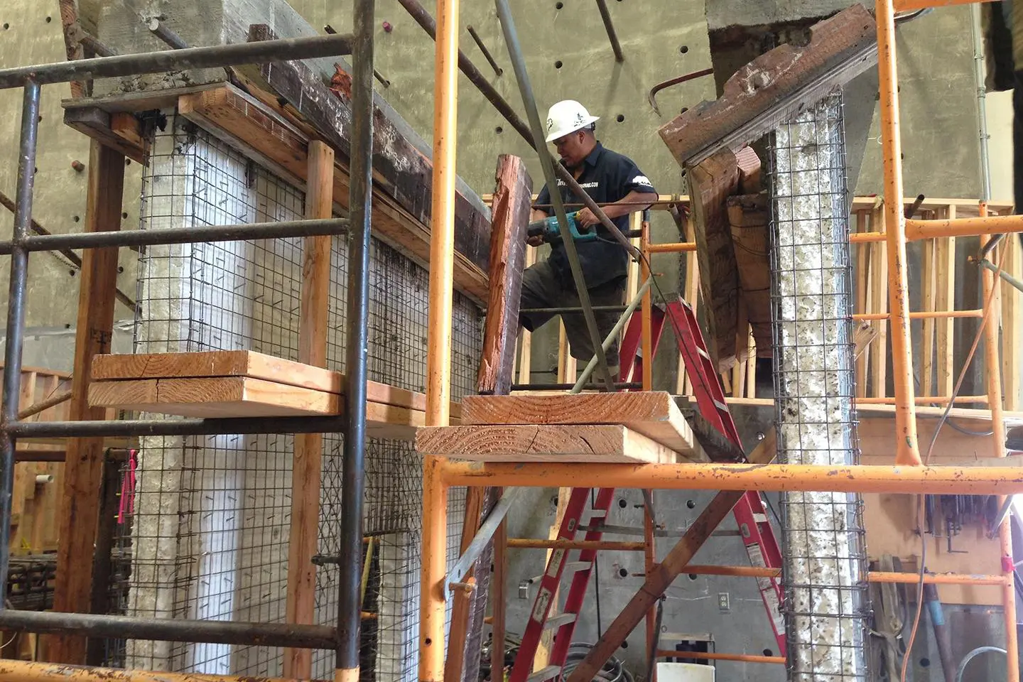 A man on a ladder in the middle of construction.