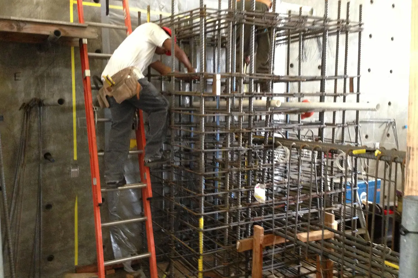 A man on a ladder working in the middle of a building.