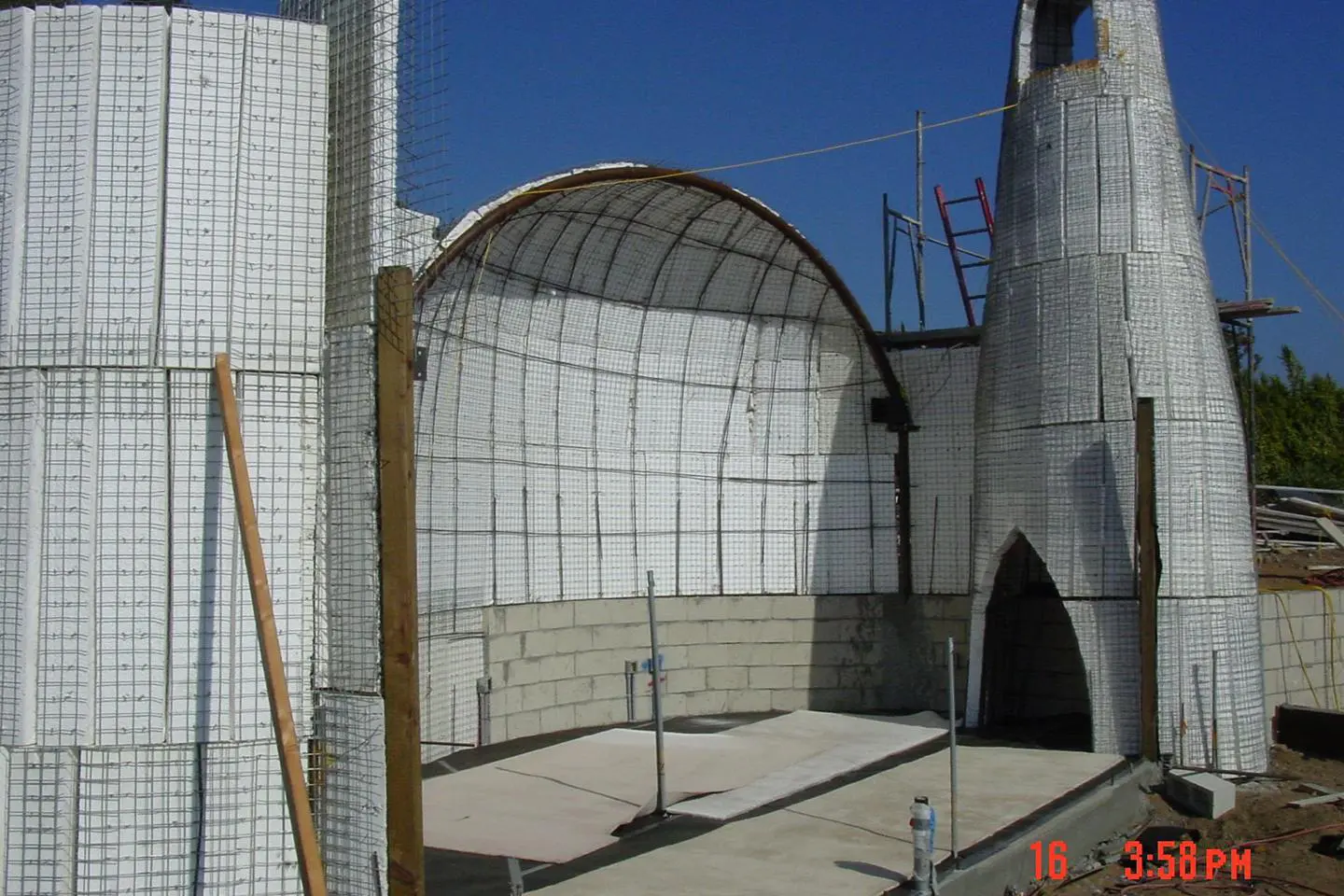 Unfinished building with arched roof and scaffolding.