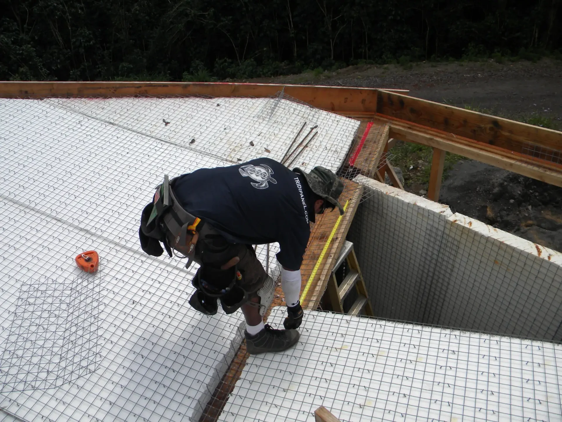 Worker installing wire mesh on roof.