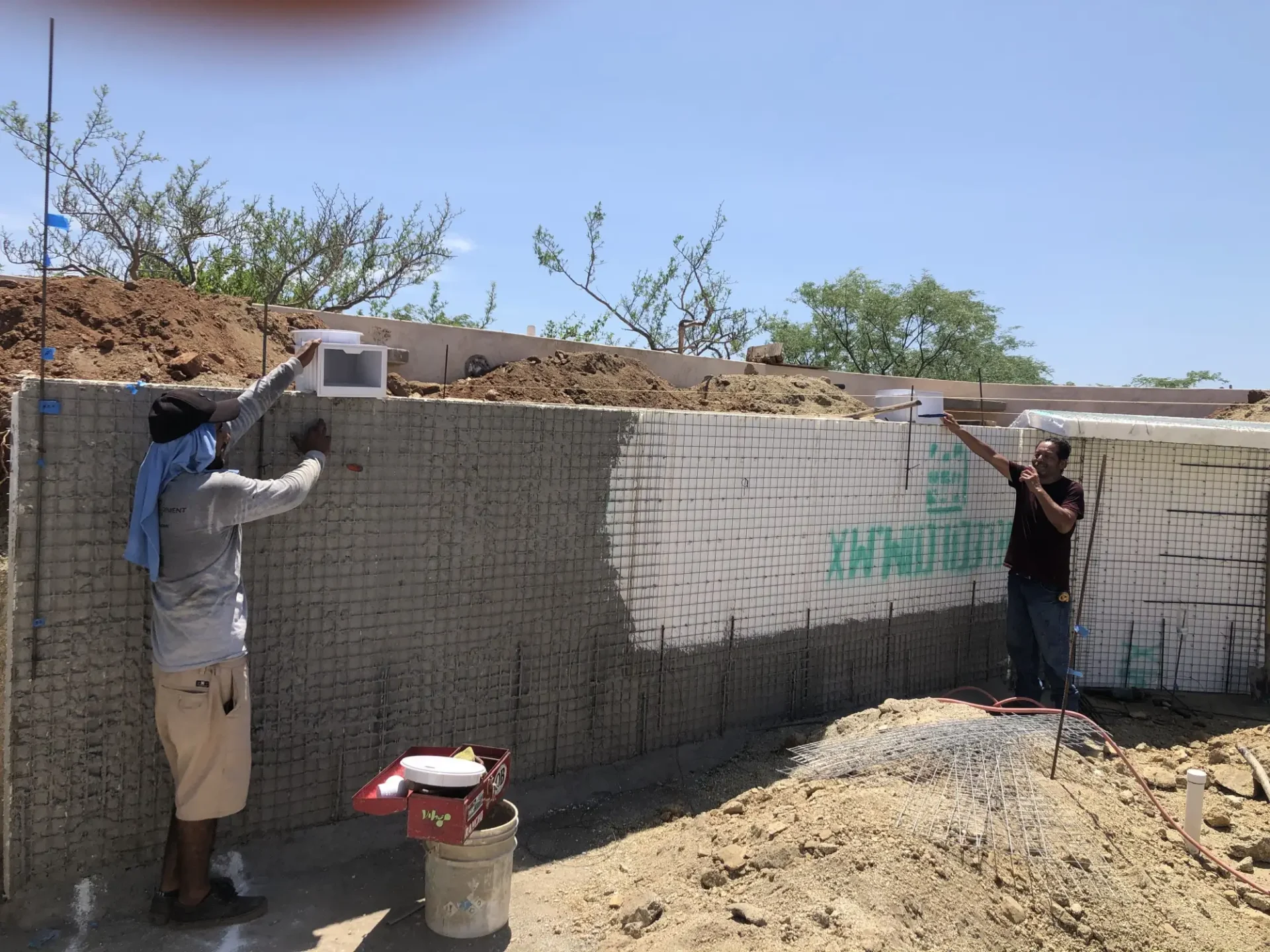 Two men working on a concrete wall.