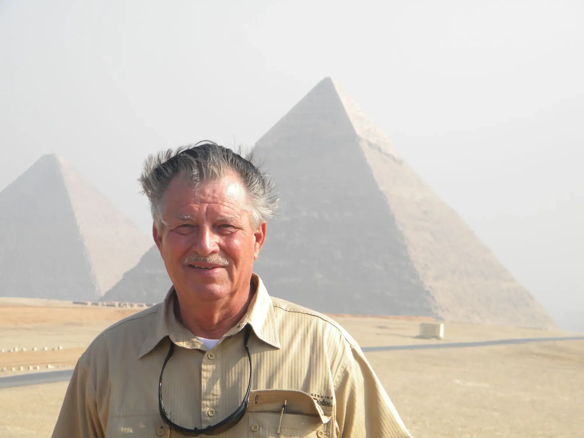 Man smiling in front of pyramids.