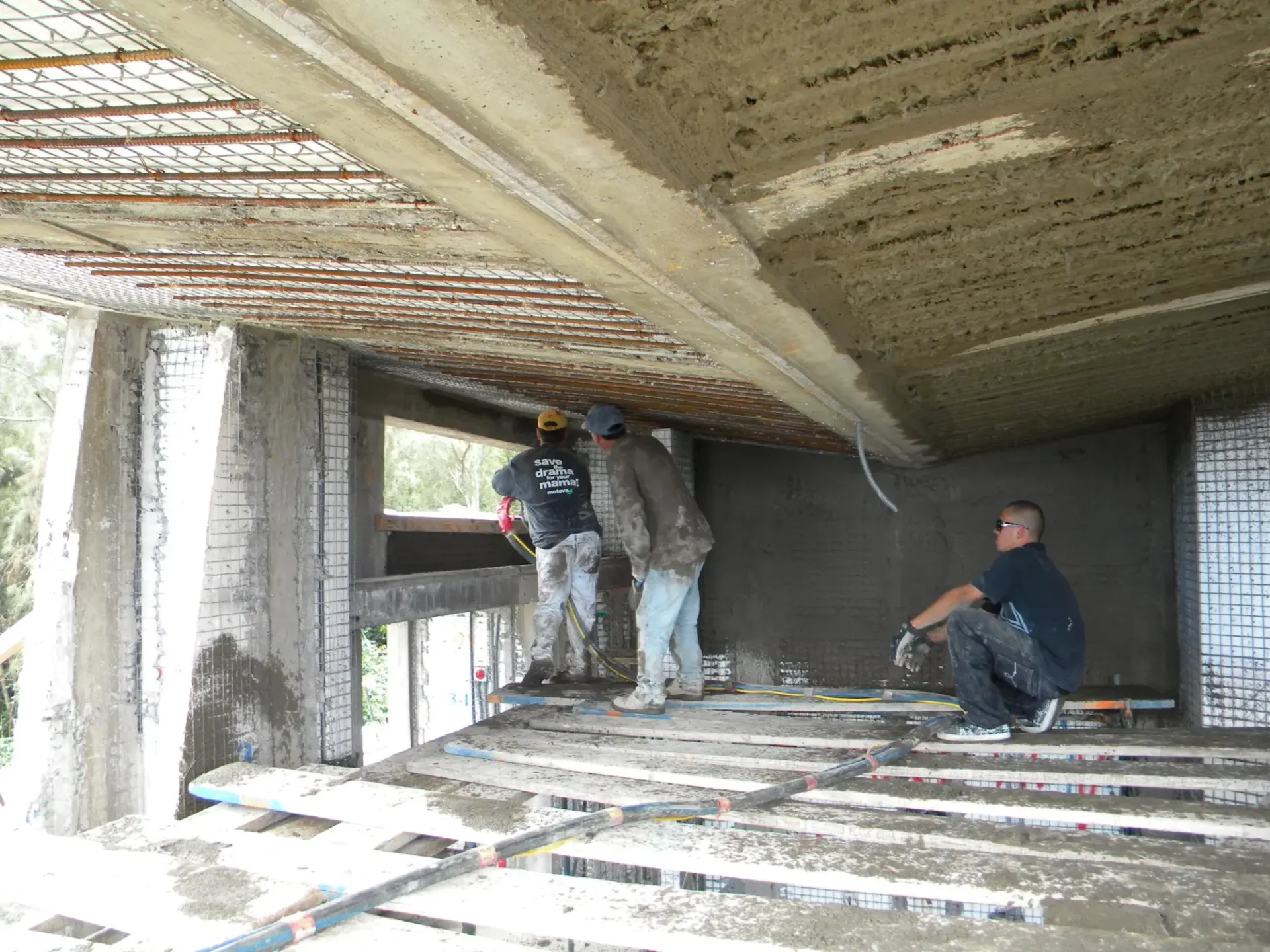 Three construction workers applying concrete.